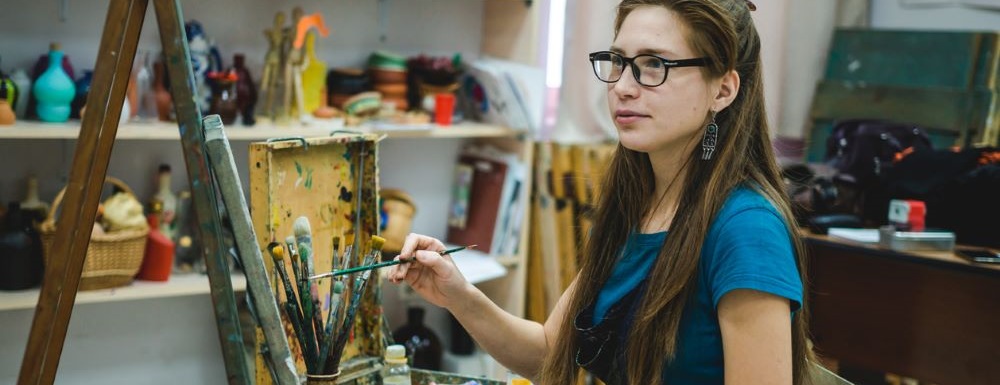 student looking at canvas with oil paints